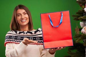 Erwachsene glückliche Frau, die Weihnachtsgeschenke auf grünem Hintergrund kauft foto
