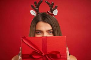 Erwachsene glückliche Frau mit Weihnachtsgeschenk auf rotem Hintergrund foto