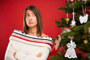 müde Frau schmücken Weihnachtsbaum auf rotem Hintergrund foto