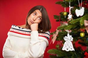 müde Frau schmücken Weihnachtsbaum auf rotem Hintergrund foto