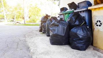 schwarze Plastikmüllsäcke auf dem Boden, die auf Recycling warten foto