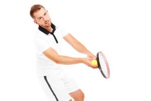 hübscher Tennisspieler, der einen Ball serviert foto