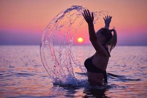 Silhouette einer jungen Frau, die bei Sonnenaufgang am Strand Yoga praktiziert foto