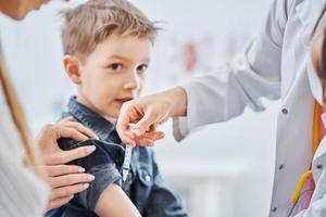 kleiner Junge wird vom Kinderarzt geimpft foto