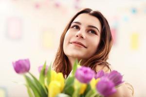 attraktive frau, die tulpenblumen in der vase arrangiert foto