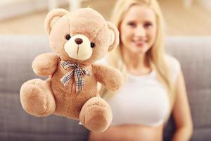 glückliche schwangere Frau mit Teddybär foto