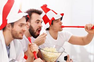 glückliche männliche freunde jubeln und sehen sport im fernsehen foto