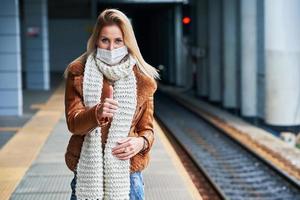 erwachsene frau am bahnhof, die aufgrund von covid-19-beschränkungen masken trägt foto