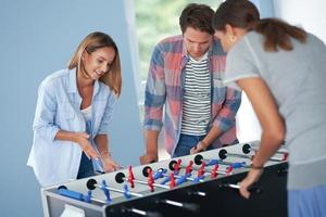 Gruppe von Studenten, die auf dem Campus Tischfußball spielen foto