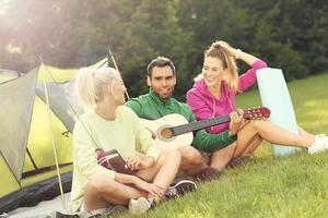 gruppe von freunden, die im wald campen und gitarre spielen foto