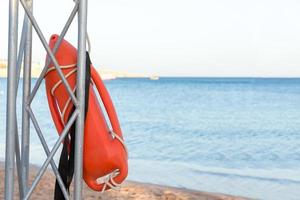 Strand lebensrettend. Rettungsschwimmerturm mit orangefarbener Boje am Strand. Rettungsboje am eisernen Rettungspfosten foto