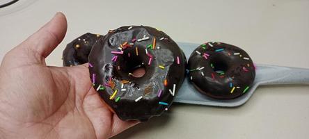 verschiedene donuts mit schokoladenglasur, rosa glasierten und bestreuten donuts. Donuts in der Hand oder Tablett foto
