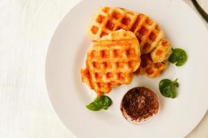 Croissant-Waffel oder Croffle mit Schokoladensauce, serviert in Schachtel und weißem Hintergrund foto