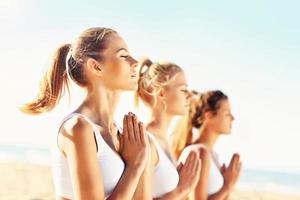 Gruppe von Frauen, die Yoga am Strand praktizieren foto