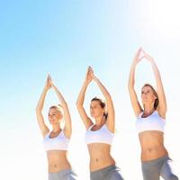 Gruppe von Frauen, die Yoga am Strand praktizieren foto