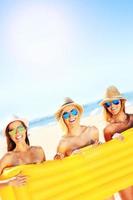 Gruppe von Frauen, die sich mit einer Matratze am Strand amüsieren foto