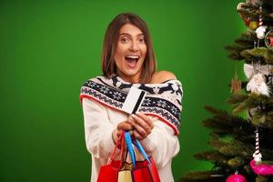 Erwachsene glückliche Frau, die Weihnachtsgeschenke auf grünem Hintergrund kauft foto