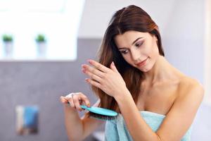 junge frau, die im badezimmer steht und haare bürstet foto