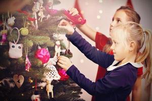 Kinder, die Weihnachtsbaum schmücken foto