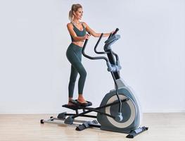 Frau, die im Fitnessstudio auf dem Crosstrainer trainiert foto