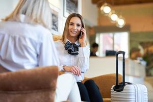 Zwei Geschäftsfrauen mit Gepäck in der modernen Hotellobby foto