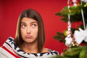 müde Frau schmücken Weihnachtsbaum auf rotem Hintergrund foto