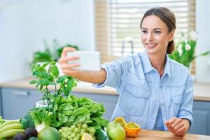 Gesunde erwachsene Frau mit grünem Essen in der Küche foto