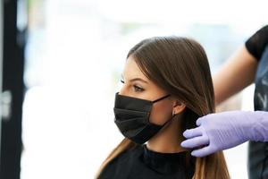 erwachsene frau beim friseur, die wegen einer coronavirus-pandemie eine schutzmaske trägt foto