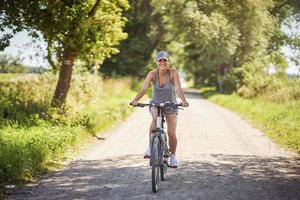 junge glückliche Frau auf einem Fahrrad in der Landschaft foto