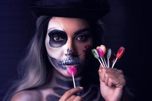 gruseliges porträt einer frau in halloween-gotischem make-up, das lillipops hält foto