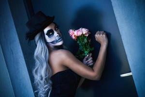 gruseliges porträt einer frau in gotischem halloween-make-up, das an die tür klopft foto