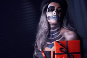 gespenstisches porträt der frau im halloween-gotischen make-up, das präsent hält foto