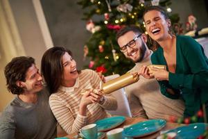 gruppe von freunden, die weihnachten feiern, indem sie cracker ziehen foto