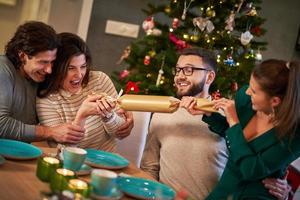 gruppe von freunden, die weihnachten feiern, indem sie cracker ziehen foto