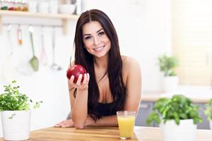 Passen Sie lächelnde junge Frau mit gesundem Saft in der modernen Küche an foto