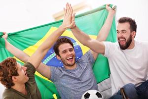 glückliche männliche freunde jubeln und sehen sport im fernsehen foto