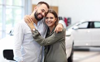 erwachsenes paar, das neues auto im ausstellungsraum auswählt foto