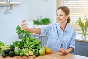 Gesunde erwachsene Frau mit grünem Essen in der Küche foto