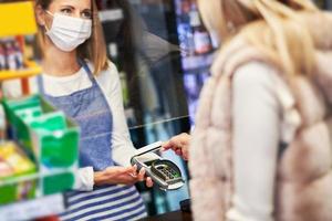 erwachsene Frau in medizinischer Maske, die Lebensmittel einkauft foto