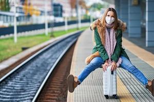 erwachsene frau am bahnhof, die aufgrund von covid-19-beschränkungen masken trägt foto