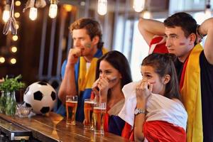 Gruppe von Freunden, die in der Kneipe Fußball schauen foto