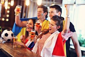 Gruppe von Freunden, die in der Kneipe Fußball schauen foto