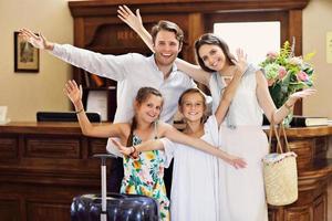 glückliche familie checkt im hotel an der rezeption ein foto