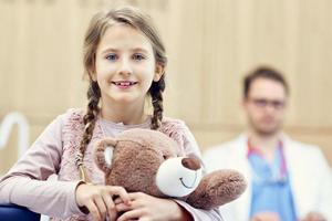 kleines Mädchen in der Klinik mit Kinderarzt im Hintergrund foto