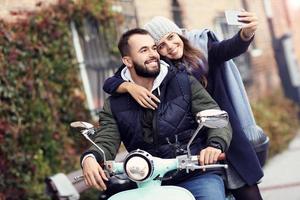 Schönes junges Paar lächelt beim Rollerfahren in der Stadt im Herbst foto