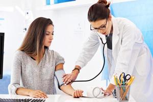 Erwachsene Frau mit Blutdrucktest während des Besuchs in der Arztpraxis foto