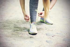 Frau joggt im Wald und bindet Schuhe foto