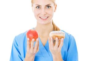 Krankenschwester hält süße Speisen und Apfel auf weißem Hintergrund foto