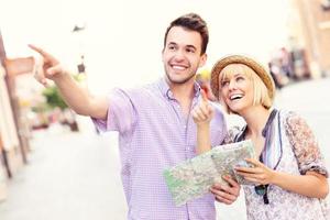 glückliche touristen, die die stadt mit einer karte besichtigen foto