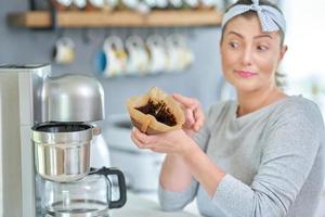 junge Frau mit Kaffeesatz verwendet es zum Schälen foto